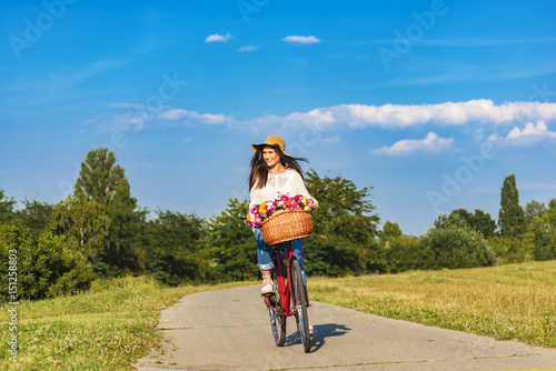 Fototapeta Naklejka Na Ścianę i Meble -  Young smiling woman rides a bicycle in counrtyside