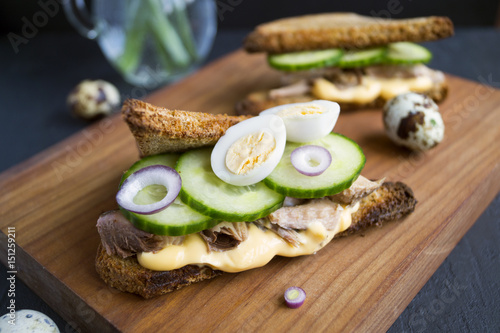 Healthy sandwich with tuna, cucumber and sauce. on a wooden Board. black background