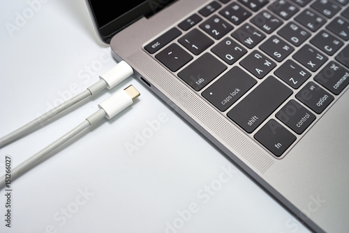 USB type C cable connected to laptop while another cable disconnected to laptop on white background