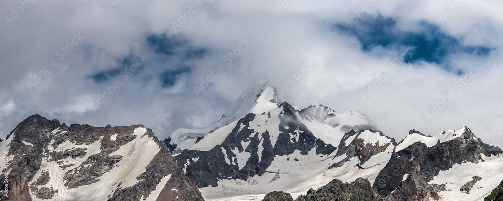 Stormy clouds over the snowy Caucasus mountains in Adyl Su gorge. Prielbrusie national park, Kabardino-Balkaria, Russia.