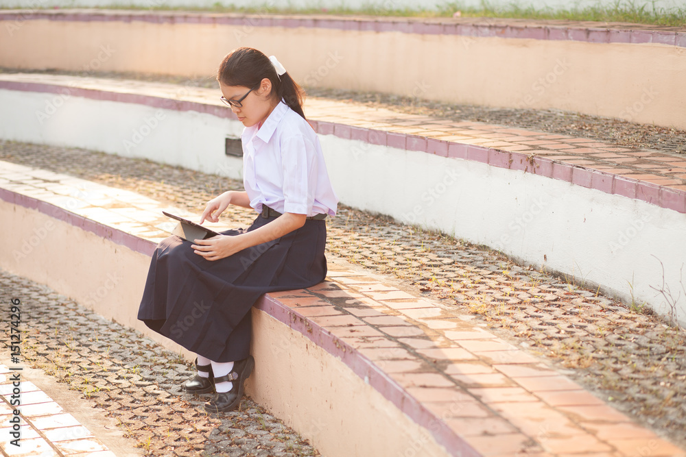 Thai student girl teenager using tablet at the park - obrazy, fototapety, plakaty 