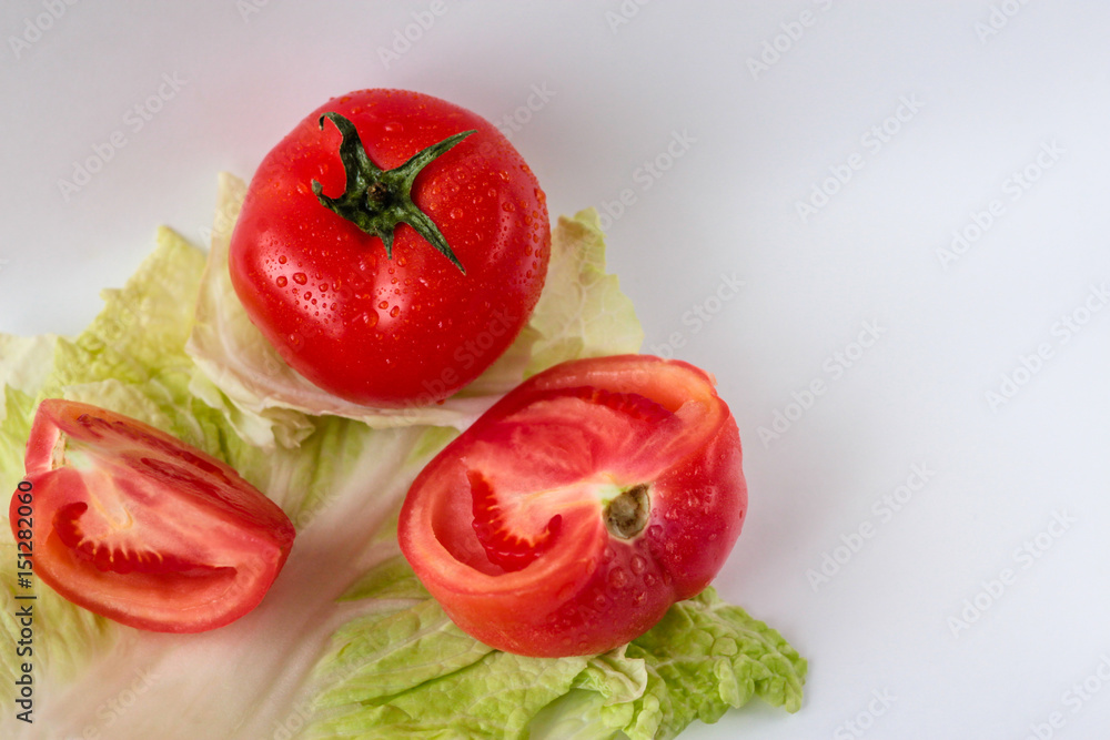 Tomato and tomato slices on a salad leaf on the white background Tomato and tomato slices on a salad leaf on the white background