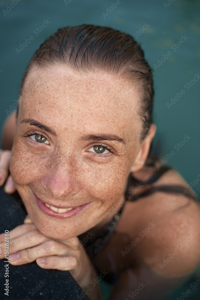 Fototapeta premium Vertical close-up portrait of beautiful girl with sunspots and wet hair in water