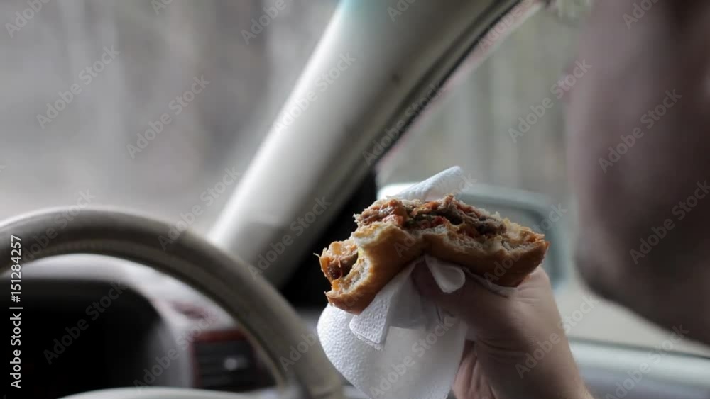 Man Eating a Burger at the Wheel of a Car Man Eating a Burger at the Wheel of a Car