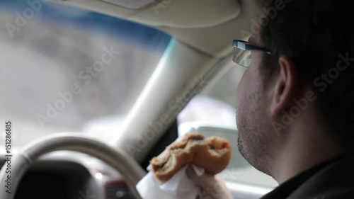 Man Eating a Burger at the Wheel of a Car