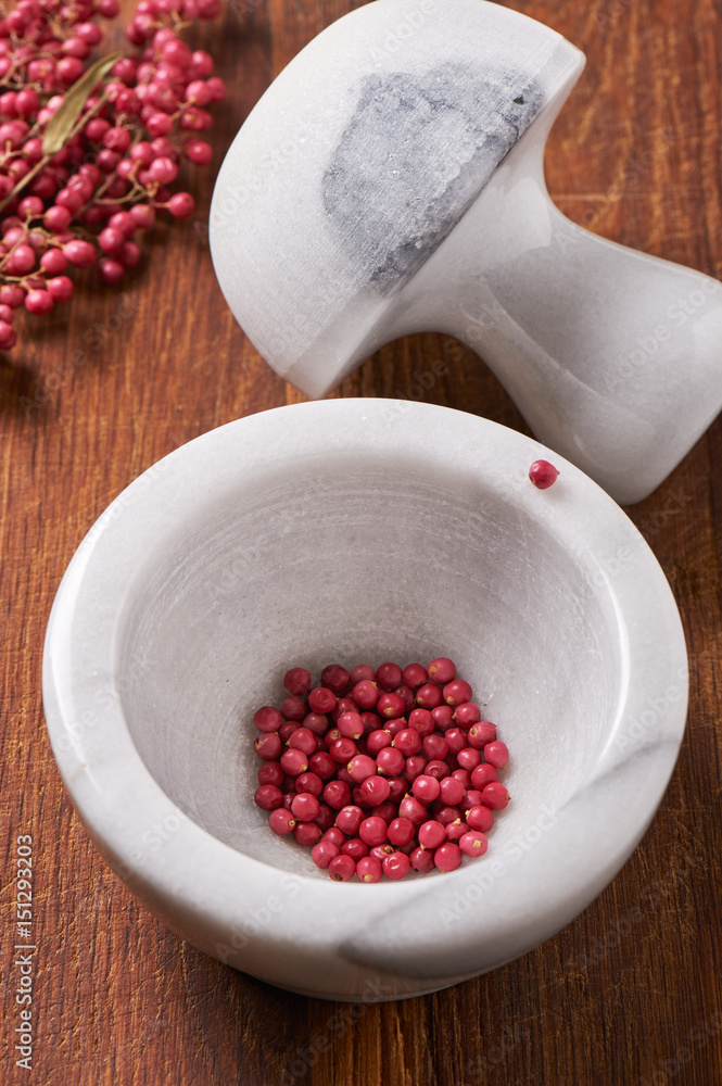 Dry rose pepper in white marble mortar next pestle Dry rose pepper in white marble mortar next pestle