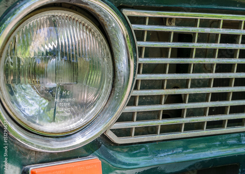 Detail of a rusty green car abandoned by the side of the road