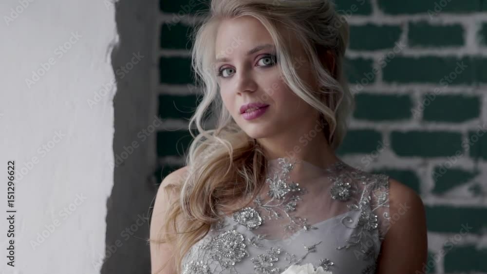 Beautiful blonde model wearing a wedding dress, posing and looking out the window. Beautiful blonde model wearing a wedding dress, posing and looking out the window.