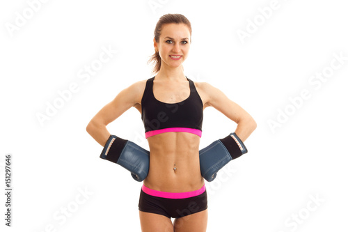 cute young girl at the top with press on her stomach stands in boxing gloves