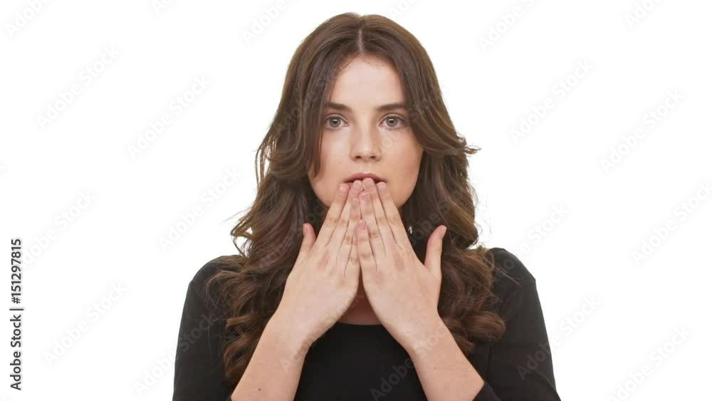 Surprised Caucasian female with burnette long hair covering mouth with hand standing on white background in slowmotion Surprised Caucasian female with burnette long hair covering mouth with hand standing on white background in slowmotion