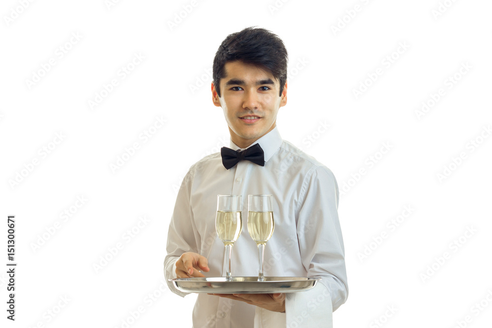 attractive young waiter in a white shirt looks straight smiles and holds on to a tray of wine glasses attractive young waiter in a white shirt looks straight smiles and holds on to a tray of wine glasses