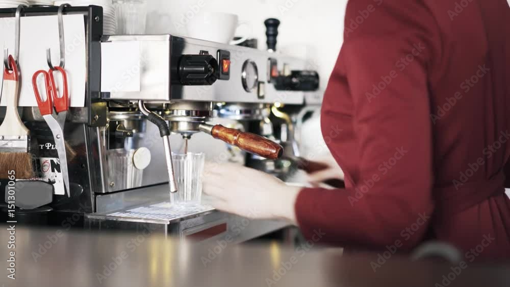 Side view of a woman barista making coffee using coffee machine and ordering her workplace. Locked down real time medium shot Side view of a woman barista making coffee using coffee machine and ordering her workplace. Locked down real time medium shot