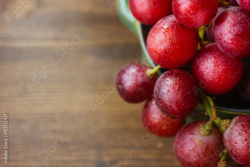 bunch of grapes on ceramic bowl over the wooden background