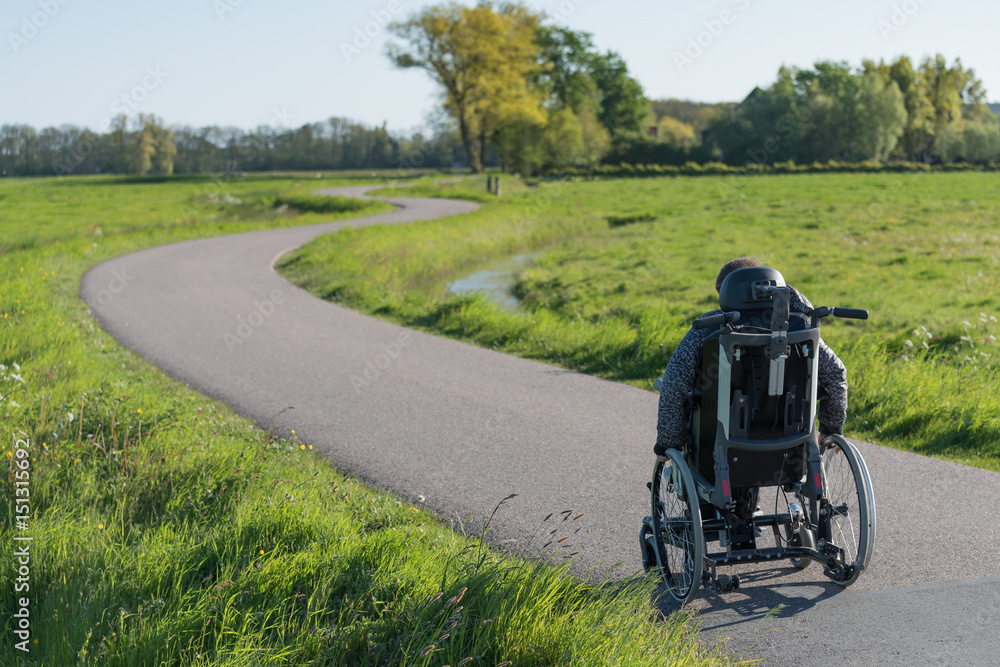 A disabled person in a wheelchair going along a long and winding road A disabled person in a wheelchair going along a long and winding road
