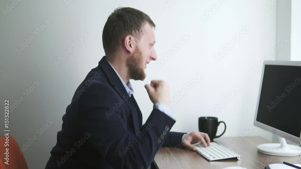 Businessman working in the office and using his computer while receiving Email with good news and making Victory gestures. Shot in slowmotion