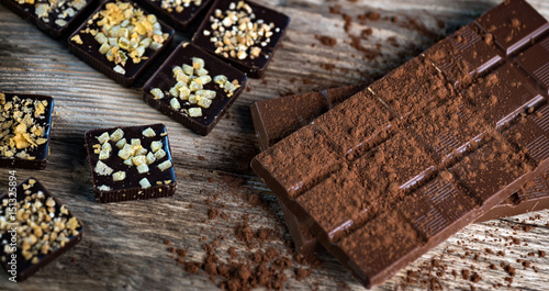 Chocolate bar pieces with cocoa powder. Background with chocolate. Slices of chocolate, Copyspace