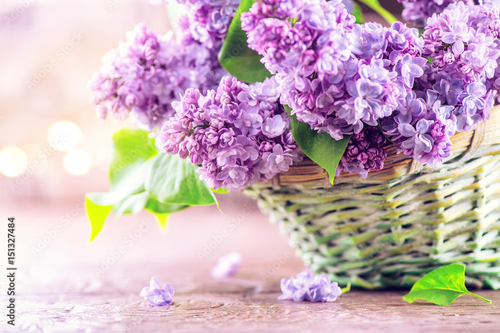 Lilac flowers bunch in a basket over blurred wood background