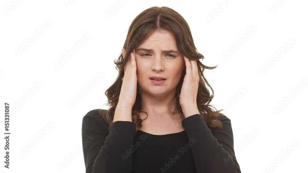 Tired Caucasian brunette female trying calm down massaging temples standing on white background in slowmotion Tired Caucasian brunette female trying calm down massaging temples standing on white background in slowmotion