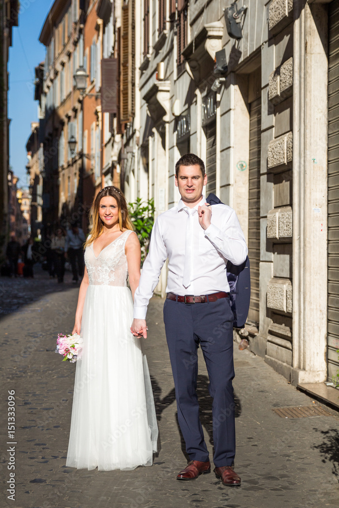 Young beautiful bride and groom on the wedding walk through the streets of old Rome, Italy.