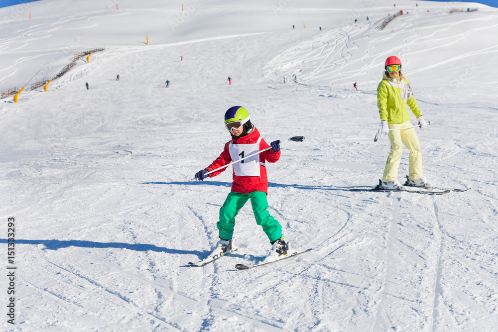 Boy learning downhill skiing with instructor