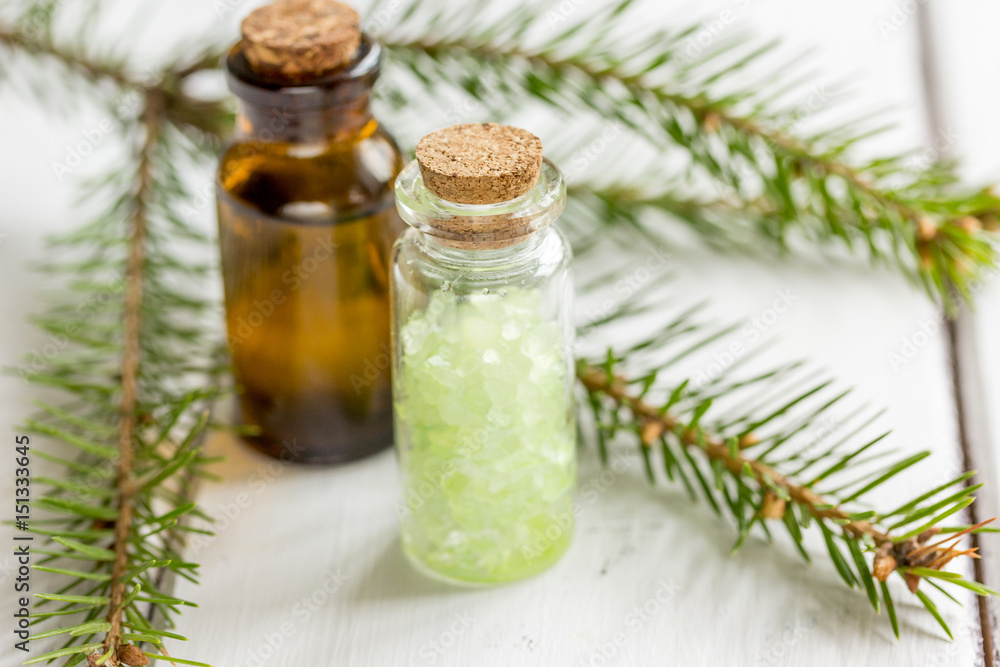 Spruce needle aromatherapy essential oils and salt in bottles on white table background Spruce needle aromatherapy essential oils and salt in bottles on white table background