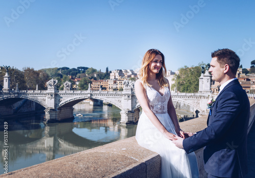 Bride and groom wedding poses on the bank of the river Tiber looking, Rome, Italy