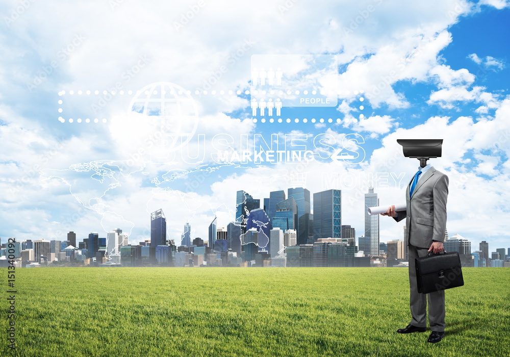 Camera headed man standing on green grass against modern cityscape Camera headed man standing on green grass against modern cityscape