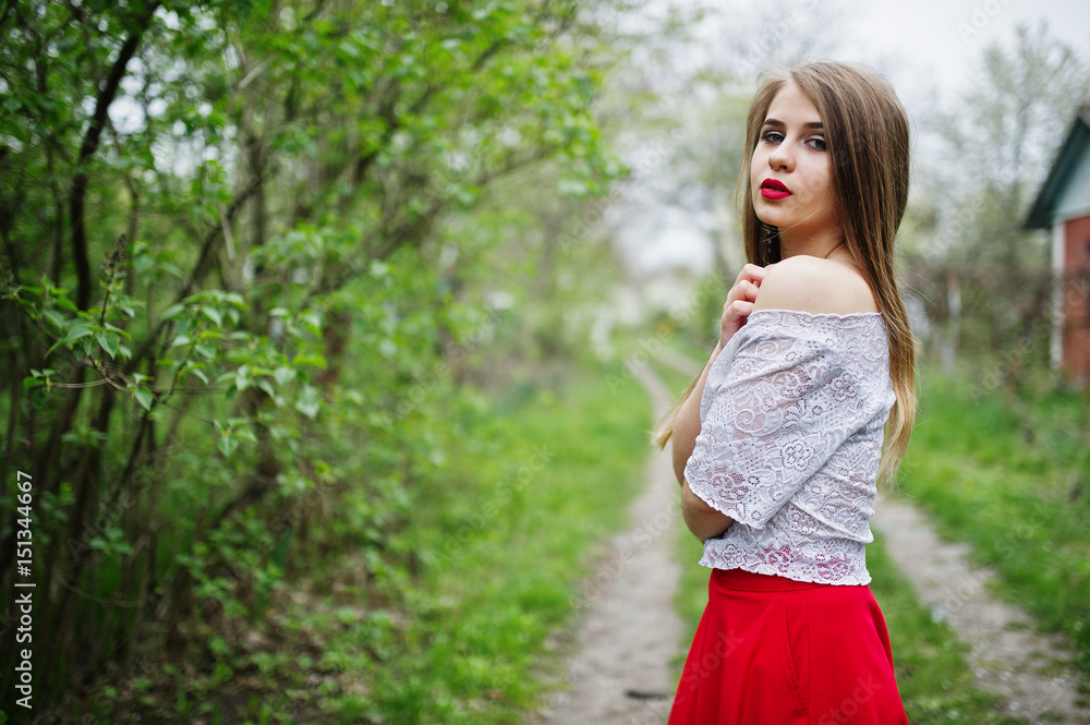 Portrait of beautiful girl with red lips at spring blossom garden, wear on red dress and white blouse. Portrait of beautiful girl with red lips at spring blossom garden, wear on red dress and white blouse.