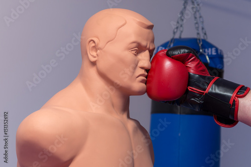 Foto Red boxing gloves punching a dummy mannequin doll on a gym with a blue punching