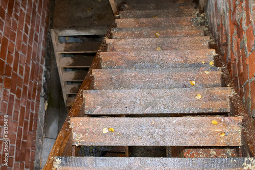 Wet wooden staircase in a brick building under construction.