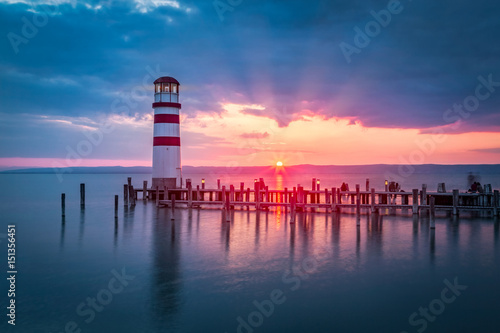 Lakeside sunset scenery with lighthouse on a peer