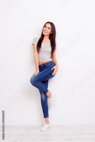 Full length portrait of gorgeous playful lady. She is wearing casual outfit and stands on pure white background