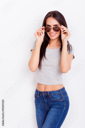 Attractive playful girl with nice smile in stylish spectacles is fixing them on the pure white background. She is flirty and tempting © deagreez