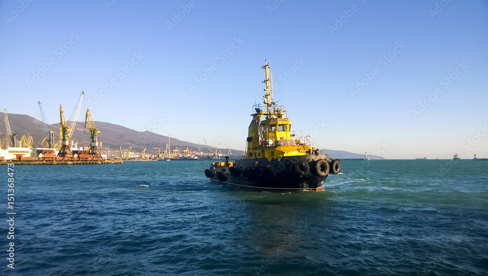 Fototapeta premium A small service ship in a cargo industrial port. A ship in the s