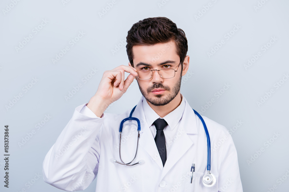 Portrait of serious confident young doctor touching his glasses Portrait of serious confident young doctor touching his glasses