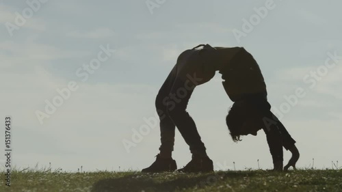 Male silhouette contortionist walking on his hands and feet whilst bent over backwards