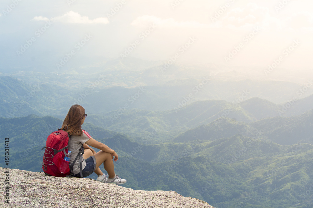 Woman with backpack sit in the mountains in summer at sunset