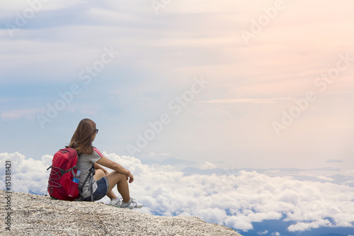 Woman with backpack sit in the mountain mist in summer at sunset © kromkrathog
