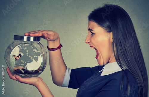 Tableau sur toile Angry woman holding a glass jar with a man working on laptop trapped inside