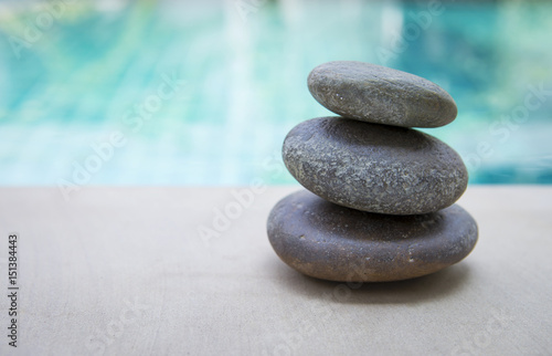 Photography Natural Zen stone stack over blurred blue swimming pool background, outdoor day