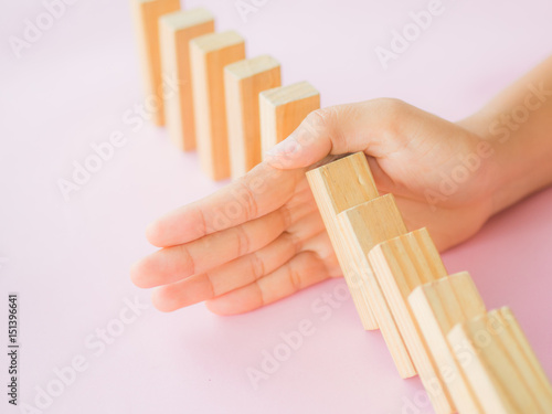 Solution concept with hand stopping wooden blocks from falling in the line of domino