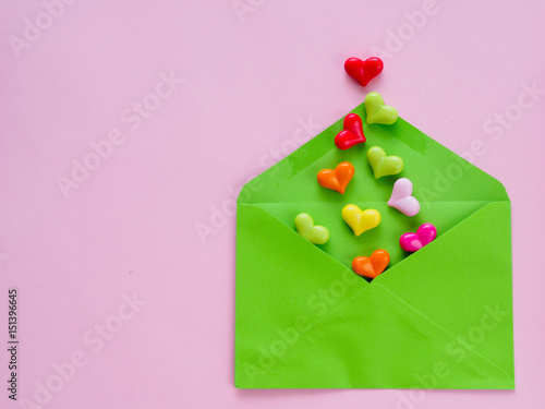 Love letter valentine's day concept. Closeup image of blue letter with copy space arranged on pink background  and colorful of hearts photo