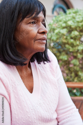 African American senior woman sitting on a bench.