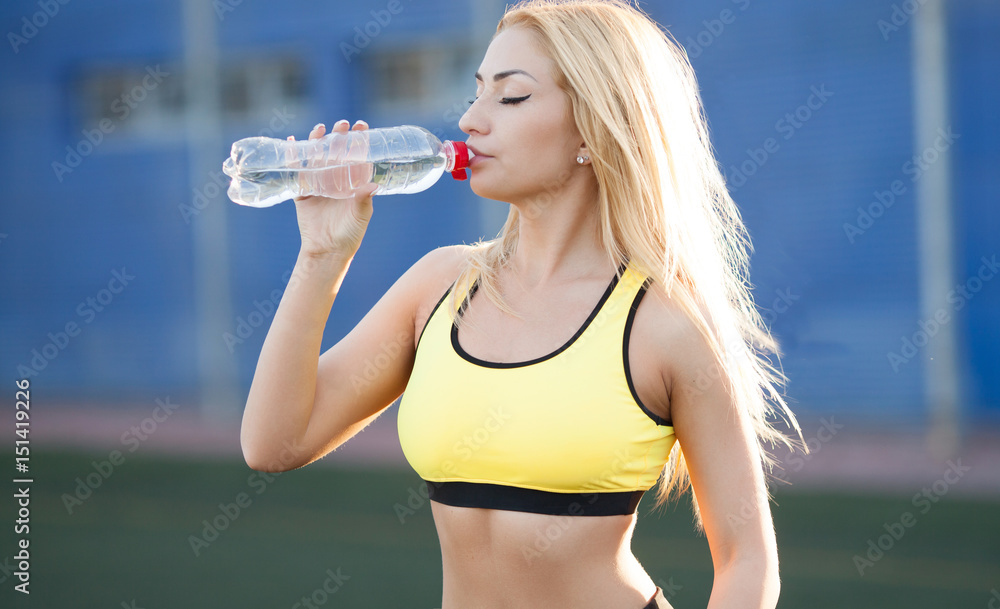 Slim young woman drinking water after training Slim young woman drinking water after training