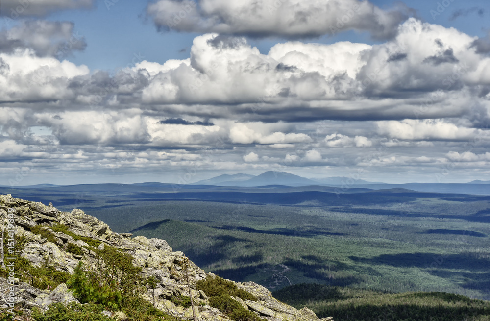 landscape Ural mountains, cliffs, rocks, sky with clouds and blue mountains in the background, tourism in Russia