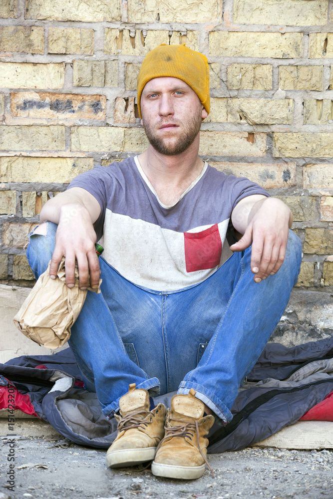 Sad homeless man with alcohol bottle . Social problem