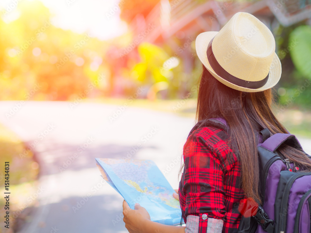 Happy Asian girl holding map with backpack in the road and forest background, Relax time on holiday concept travel ,color of vintage tone and soft focus