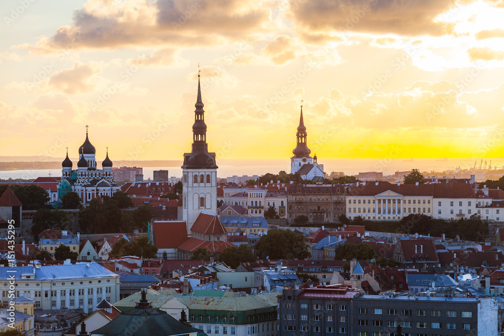 Orange sunset over old town of Tallinn, Estonia. Cathedrals towers and medieval buildings aerial view.