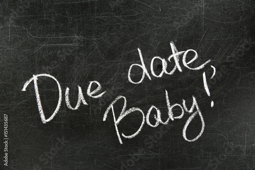 Words DUE DATE, BABY written with chalk on blackboard