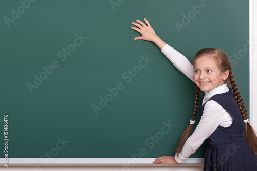 elementary school girl put hands on chalkboard background and show blank space, dressed in classic black suit, group pupil, education concept
